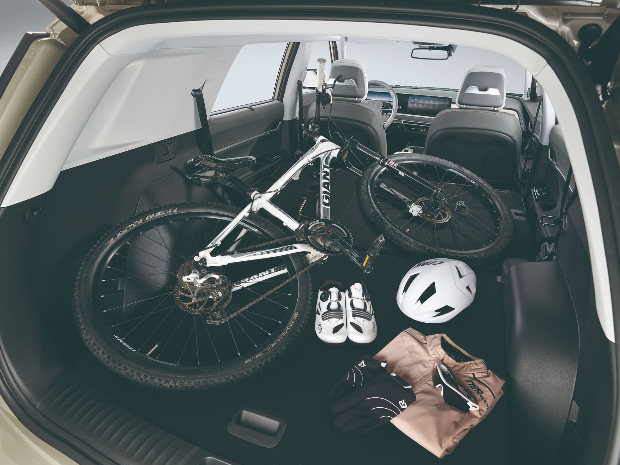 De kofferinhoud van een Torres Benzine met grijs interieur en zetels neergeklapt gevuld met een fiets, schoenen, kledij en helm.