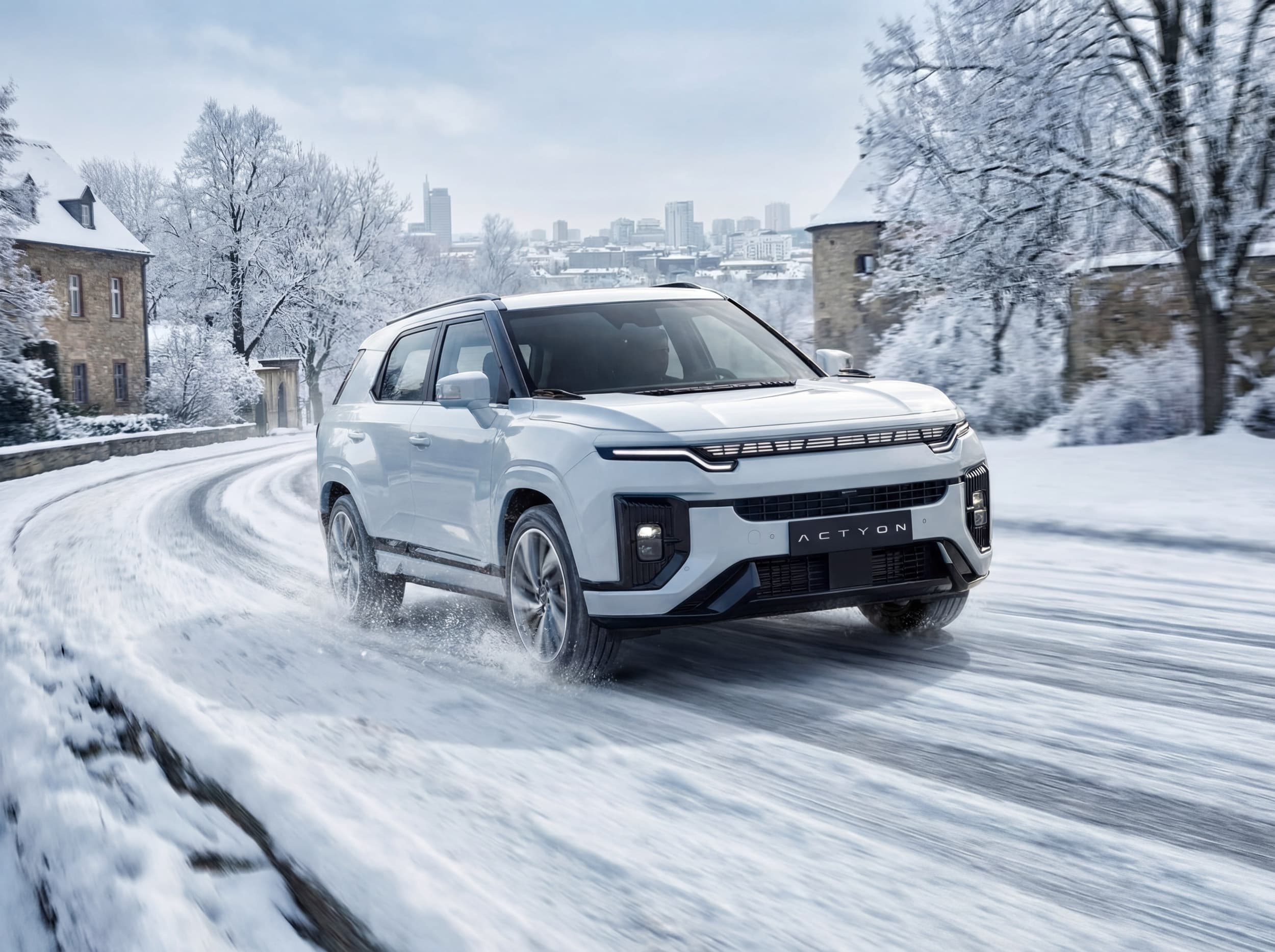 White Actyon driving on a snow-covered road in a picturesque winter landscape with trees and buildings in the background.