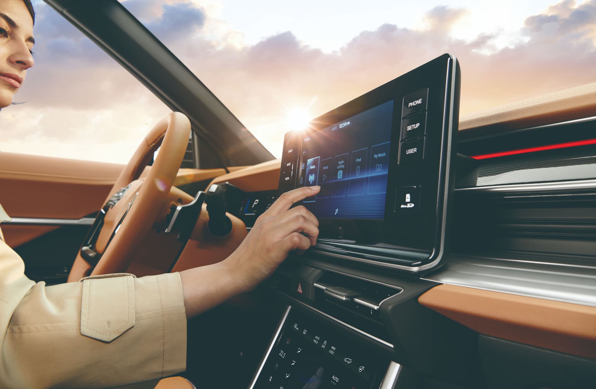 Een bruin interieur van een Torres SUV waarbij je het stuur en het audioscherm ziet waarop een vrouw iets aantikt.